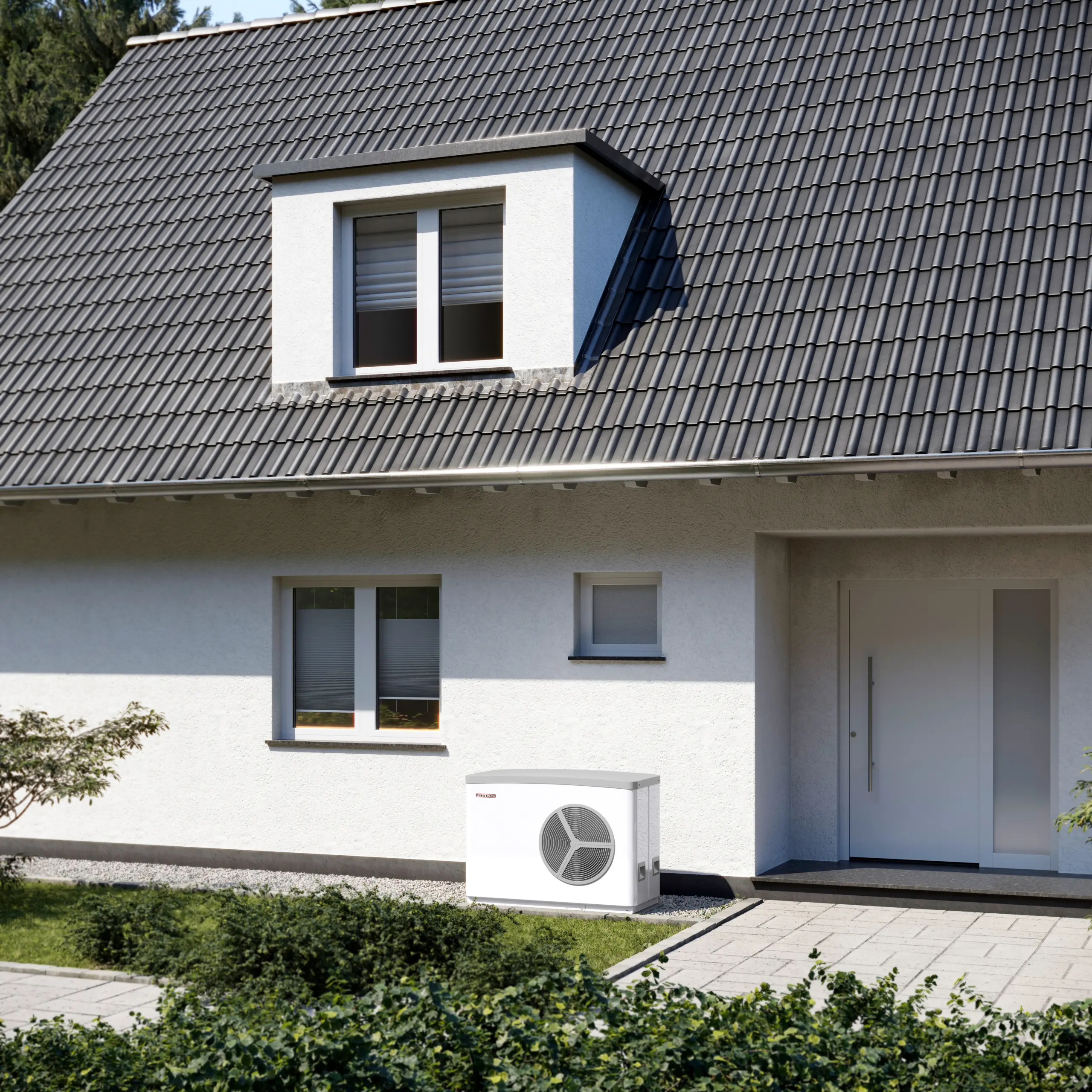 Das Bild zeigt die Außenansicht eines modernen Hauses mit einer grauen Dacheindeckung und weißer Fassade. Vor dem Haus befindet sich eine Wärmepumpe von Stiebel Eltron, die auf einer gepflasterten Fläche neben dem Eingangsbereich steht. Die Wärmepumpe ist kompakt und hat ein dezentes Design, das sich gut in die Umgebung einfügt. Der Vorgarten ist gepflegt, mit grünen Büschen und einem kleinen Baum, die dem Haus eine freundliche und einladende Atmosphäre verleihen. Das Haus hat große Fenster, die viel natürliches Licht hereinlassen, und einen klaren, modernen Eingang mit einer großen Tür. Im Hintergrund sind einige Bäume zu sehen, die dem Bild eine ruhige, natürliche Kulisse geben.